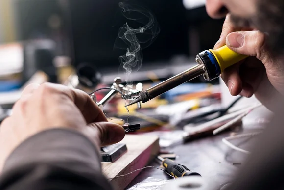 Person lötet ein elektronisches Bauteil.