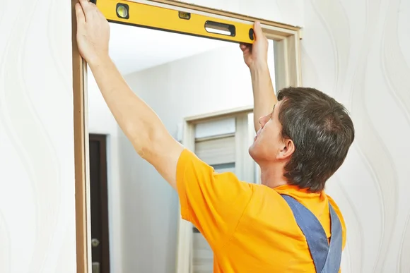 Person hält Wasserwaage an Türrahmen