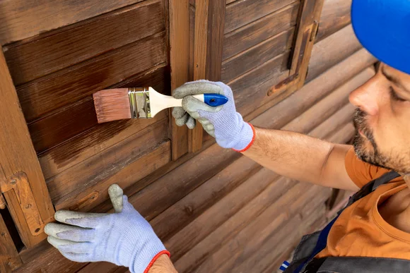 Person streicht Holz braun an