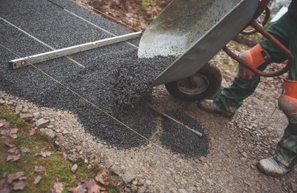 Gartenweg befestigen Eine Schubkarrenladung voller Feinsplitt wird auf den Untergrund gekippt.