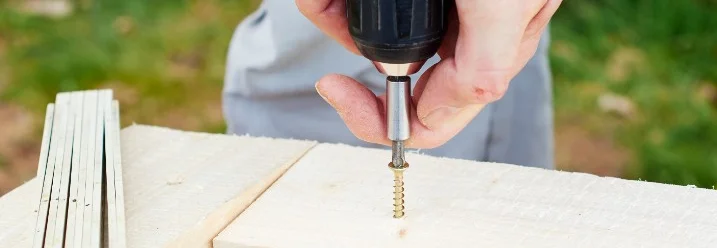Person schraubt Holzbretter zusammen