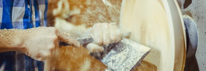 Person drechselt Holz mit Werkzeug