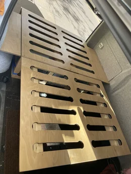 Bettkonstruktion aus Holz mit Lüftungsschlitzen in einem Fahrzeug.