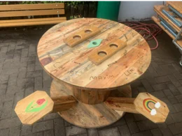 Ein runder Tisch und zwei passende Hocker aus Holz.