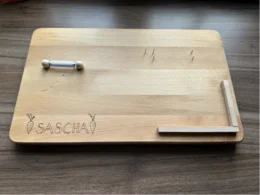 Helles Holzbrett mit Gravur und Holzdübeln.