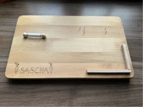 Helles Holzbrett mit Gravur und Holzdübeln.