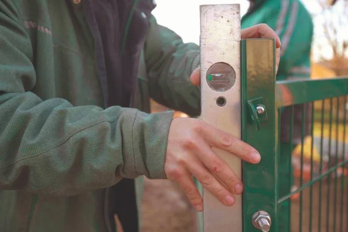 Person richtet Zaunpfosten mit Wasserwaage aus