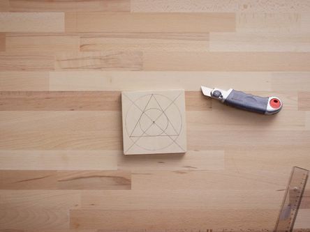 Cuttermesser, Lineal, Auf ein Stück Holz gezeichnetes Dreieck, Kreuz und Kreise