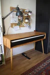 Ein E-Piano in einem Holzgehäuse in einem Arbeitszimmer.