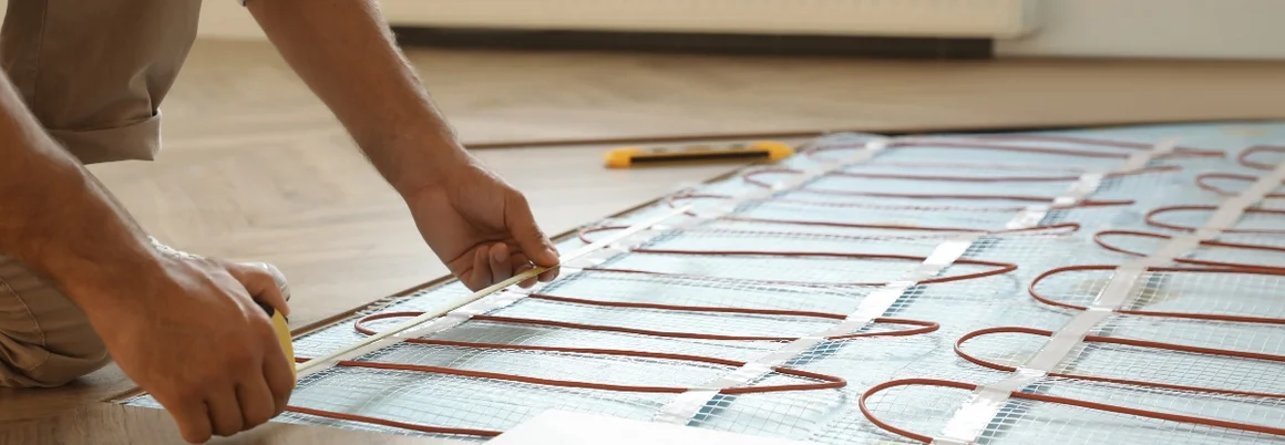 Person verlegt Heizmatten auf Fußboden.