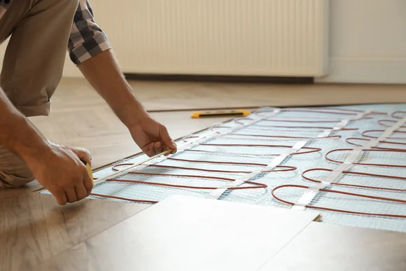 Person verlegt Heizmatten auf Fußboden.