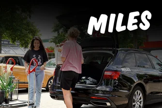 Zwei Personen laden einen Kombi vor einem toom Baumarkt ein.