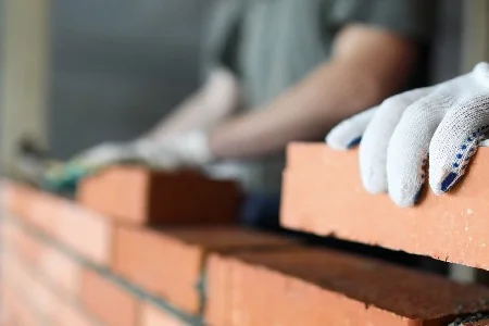 Person mauert Ziegelsteine