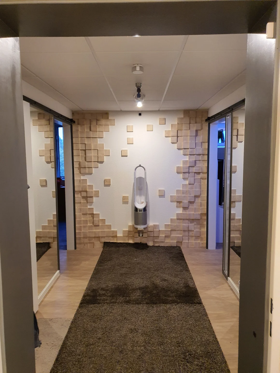 Ein modern eingerichteter Flur mit einer Akzentwand aus Holzwürfeln.