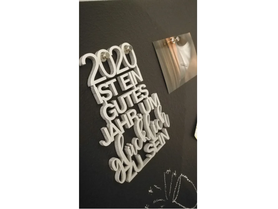 Silberfarbener Schriftzug "2020 ist ein gutes Jahr um glücklich zu sein" an schwarzer Pinnwand