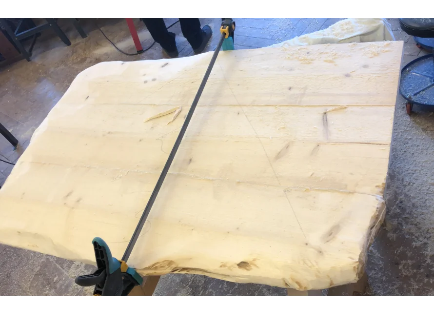 Große Holzplatte mit Bleistiftskizze und Säge