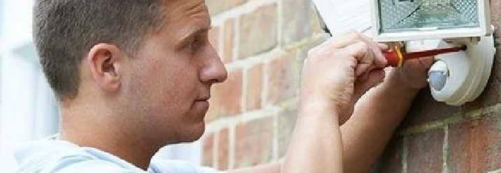 Person montiert Außenleuchte mit Schraubendreher.