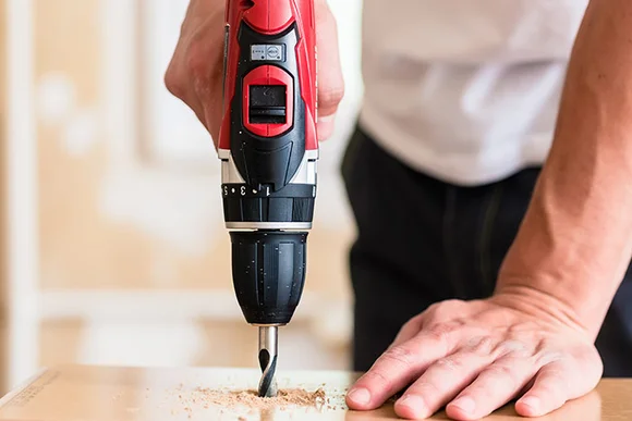 Person bohrt mit Bohrmaschine in Holz