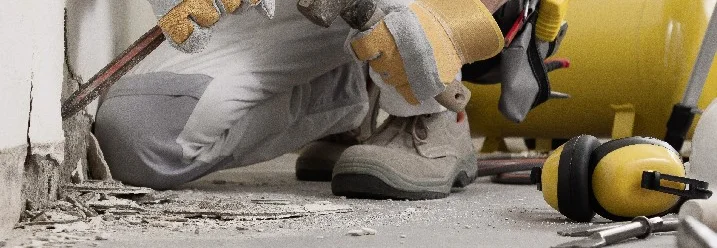 Person entfernt Putz mit Meißel