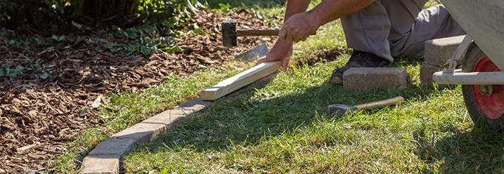 Person verlegt Rasenkantensteine
