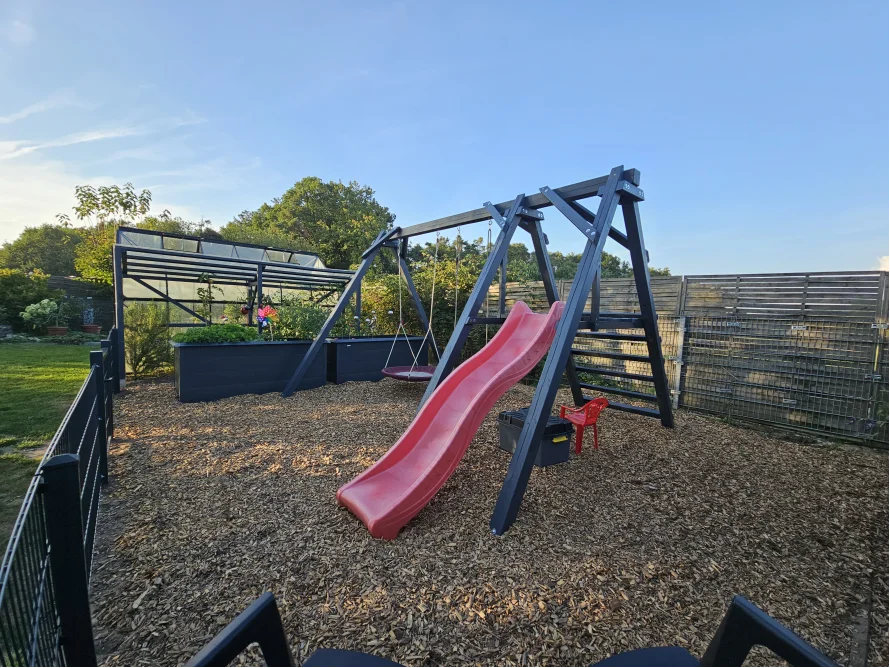 Ein Spielplatz im Garten mit Schaukel und Rutsche