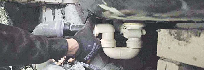 Person montiert Abflussrohre unter Badewanne