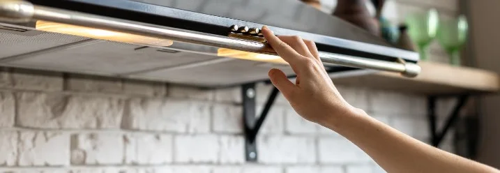 Person schaltet Dunstabzugshaube ein