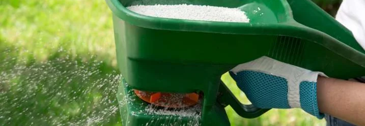 Hand streut Dünger mit Streuwagen