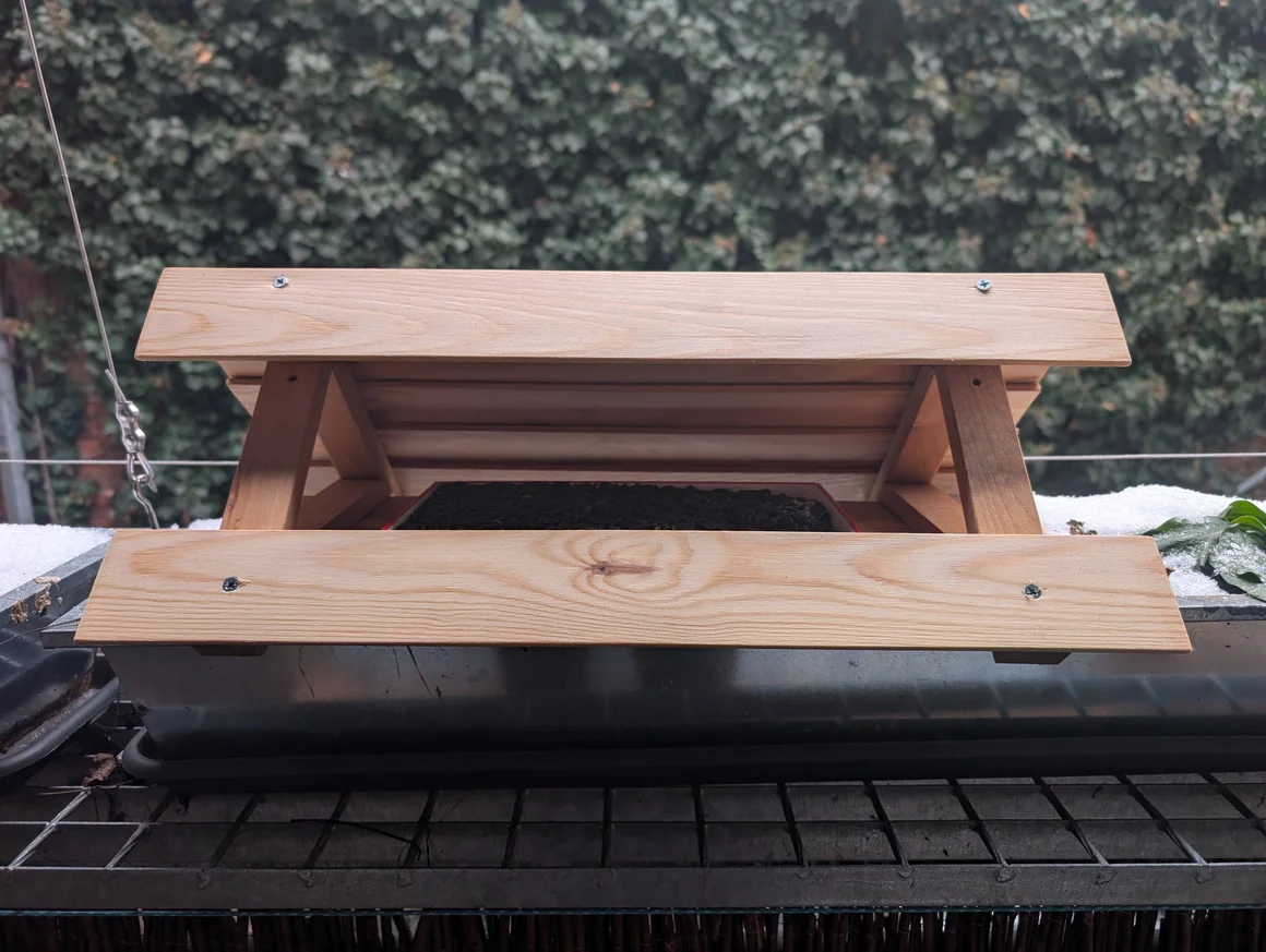 Ein Futterhaus aus Holz auf einem Gitterrost.