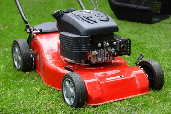 Roter Rasenmäher auf grünem Rasen