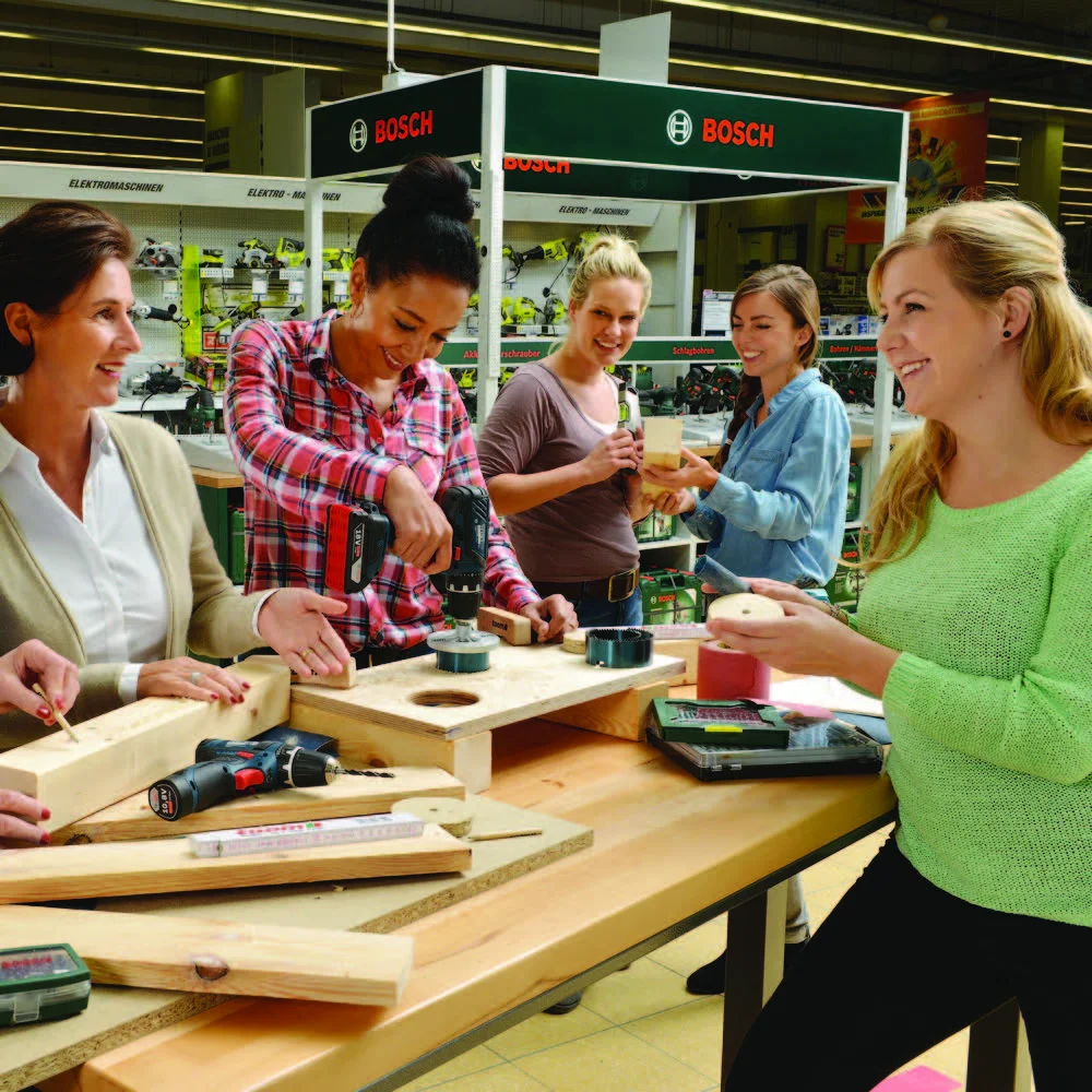 Fünf Personen bauen mit Akkuschraubern an einem Holzprojekt