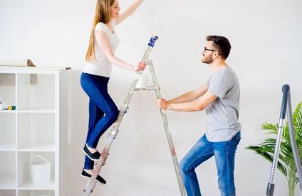 Frau und Mann steigen auf eine Leiter, um an die Decke zu kommen