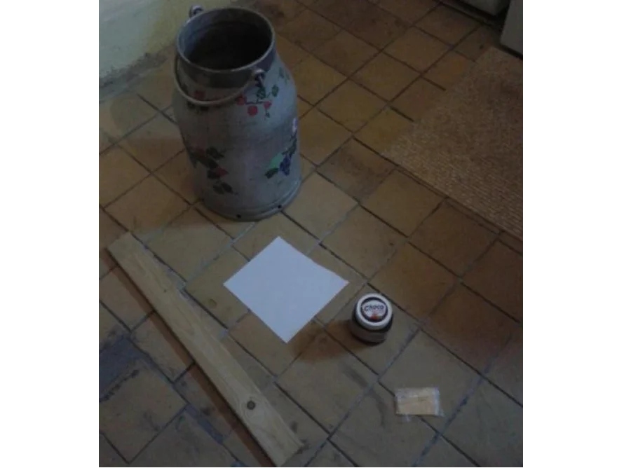 Holzlatte, Milchkrug und Dose auf Fliesenboden