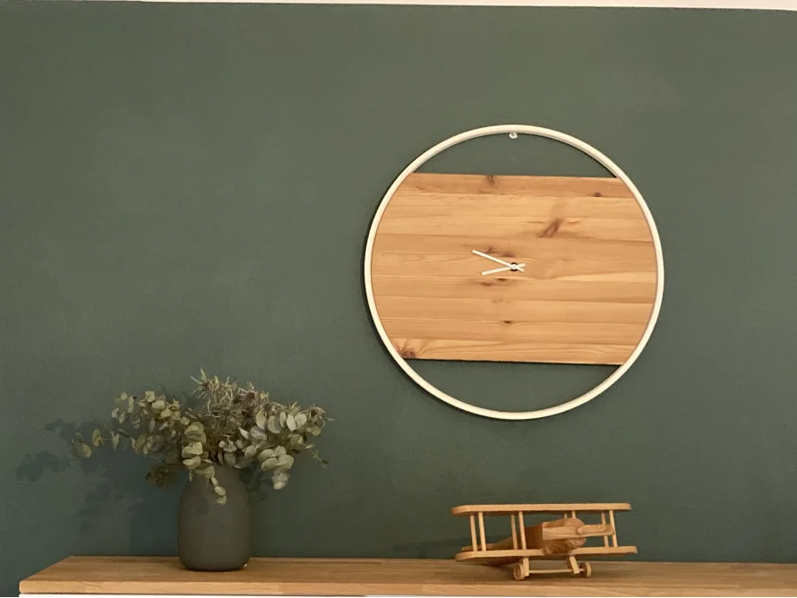 Moderne Holzuhr an grüner Wand