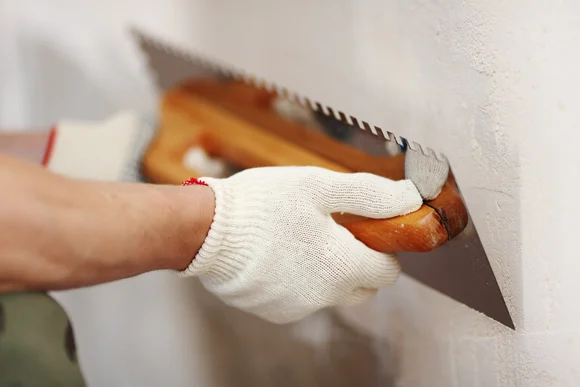 Person verputzt Wand mit Kelle