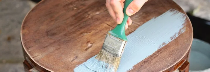 Person streicht einen Holztisch
