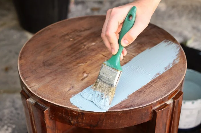 Person streicht einen Holztisch