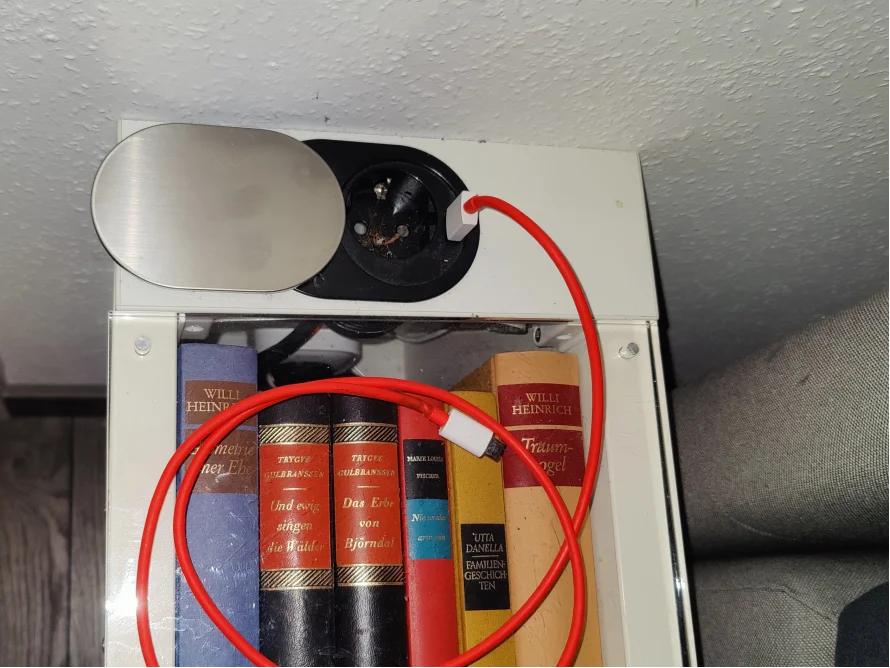 Ein rotes Ladekabel hängt an einer Steckdose