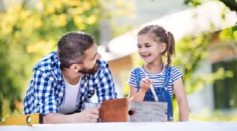 Person und Kind streichen ein Vogelhaus