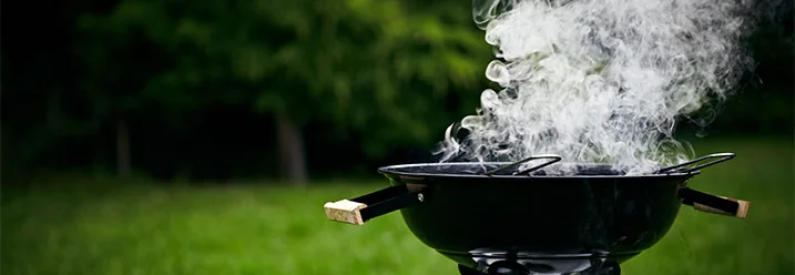 Rauchender Kugelgrill auf grünem Rasen