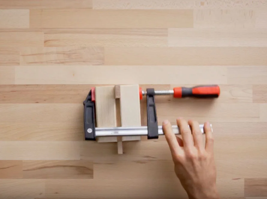 Hand fixiert Holz mit Schraubzwinge