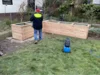 Person baut ein Hochbeet aus Holz auf