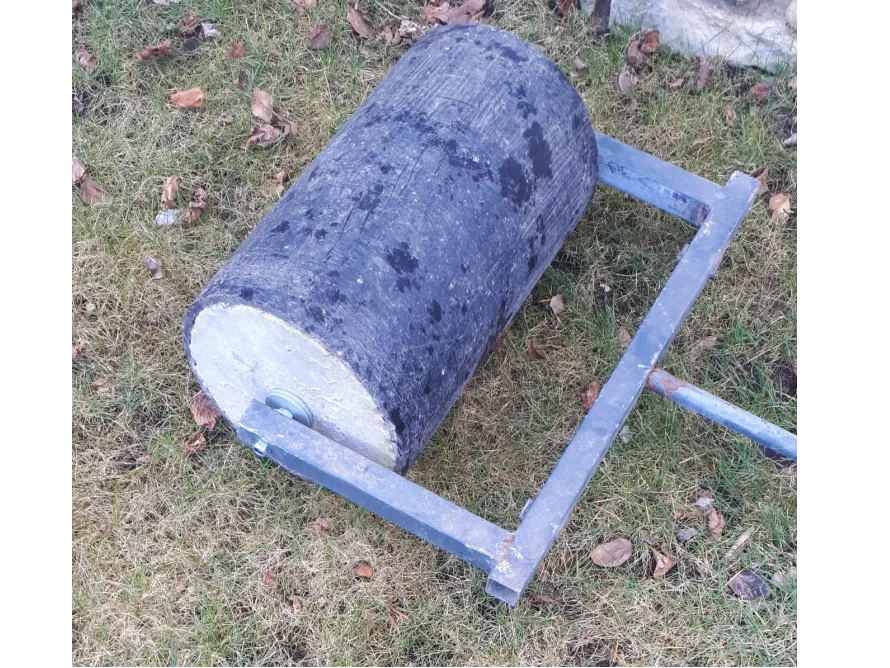 Eine Rasenwalze liegt im Gras.