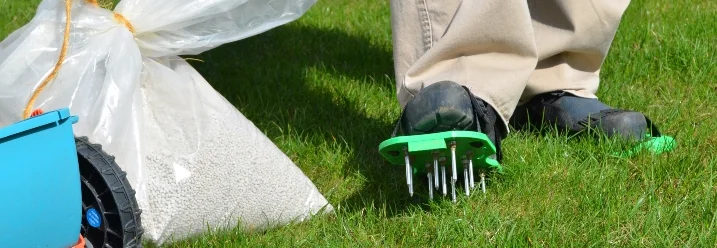 Person mit Rasenlüfterschuhen und Dünger