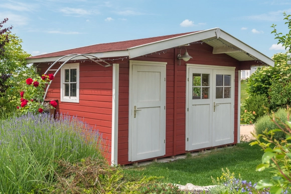 Rotes Gartenhaus in einem blühenden Garten