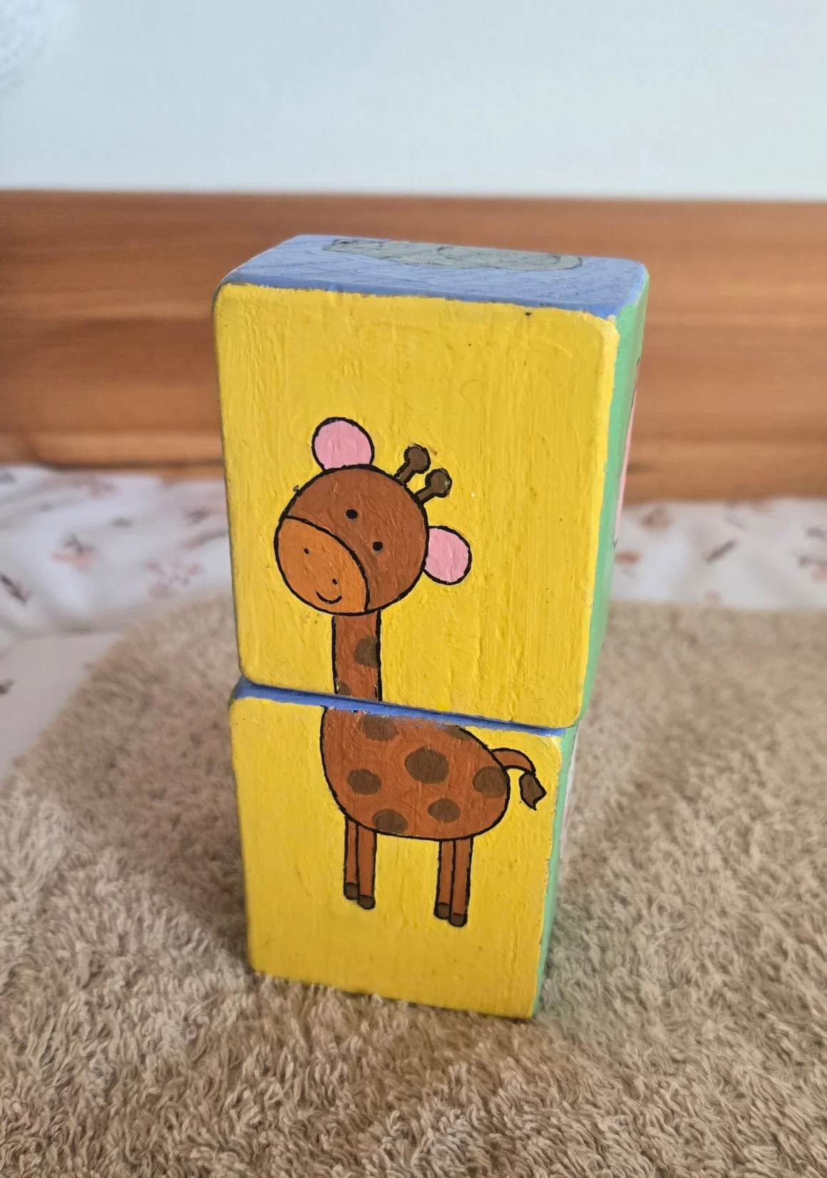 Zwei aufeinandergestapelte, bemalte Holzklötze mit einer Giraffe.