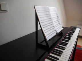 Ein schwarzes Digitalpiano mit Notenblättern auf einem Notenständer.