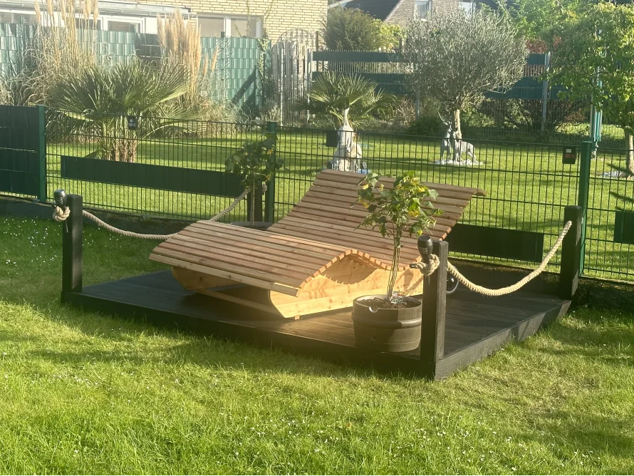 Hölzerne Liege auf Terrasse im Garten