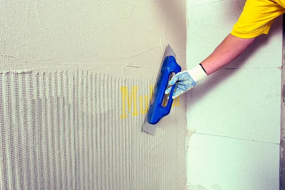 Person bringt Armierungsgewebe und Putz an