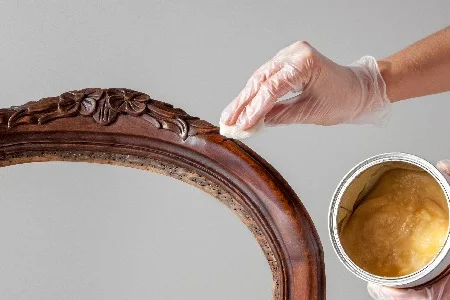 Person trägt Wachs auf einen Holzstuhl auf